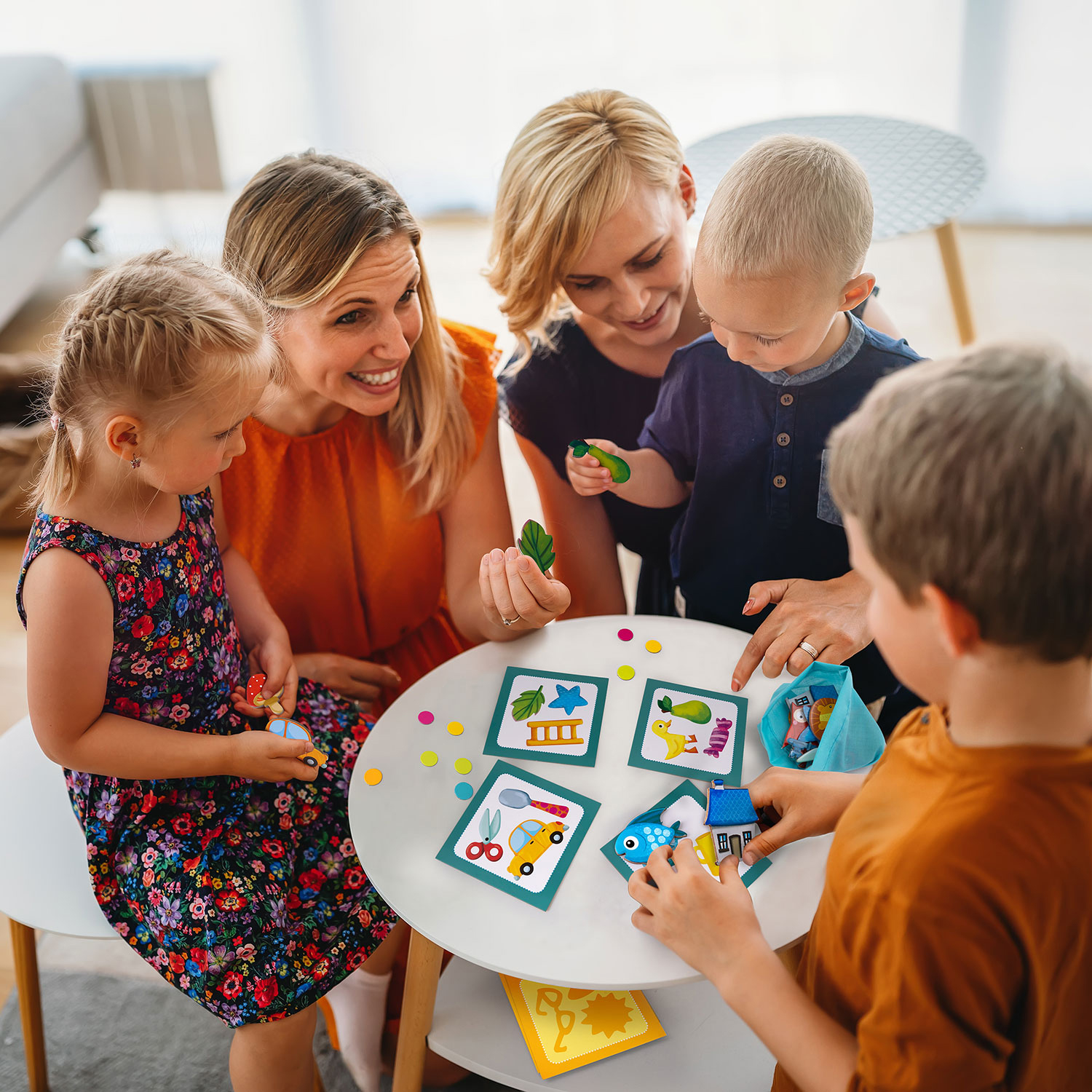 Lesbian couple at the table playing board game with children.